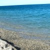 Spiaggia di ciottoli con acqua blu chiara.