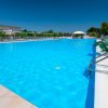 Ampia piscina con acqua azzurra, circondata da lettini bianchi.