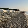 Una spiaggia con file di lettini e ombrelloni vuoti al tramonto.
