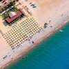 Vista aerea di una spiaggia con ombrelloni e mare.