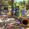 Parco giochi con altalene, scivoli e strutture colorate tra gli alberi.