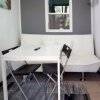 Un soggiorno minimalista con divano bianco, tavolo e sedie nere, climatizzatore e finestra.