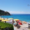 Spiaggia con ombrelloni gialli e mare blu, circondata da vegetazione.